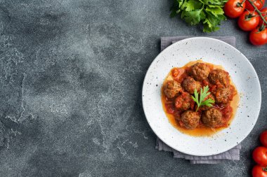 Tabakta domates sosuyla pişirilmiş köfte köftesi. Koyu beton arkaplan Kopyalama alanı.