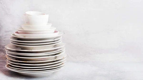 Stack of empty clean plates on a gray table with copy space