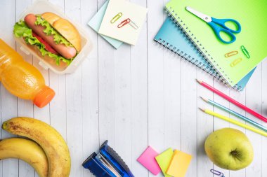 Marul domates ve sosisli sandviç. Defterler ve kırtasiye malzemeleri. Konsept okulu kahvaltısı. Boşluğu kopyala.