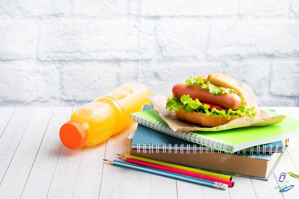 Hot dog with lettuce tomato and sausage. Notebooks and stationery. concept school Breakfast. Copy space.