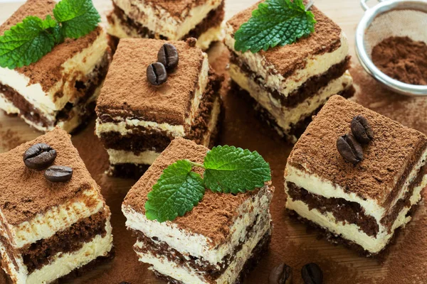 Trozos de tarta de tiramisú con delicada crema, granos de café y hojas de menta . —  Fotos de Stock