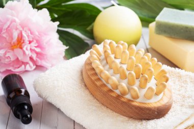 SPA ve Refah kavramı. Masaj fırçası, kozmetik yağlar ve sabun. Şakayık çiçekli hafif arkaplan.