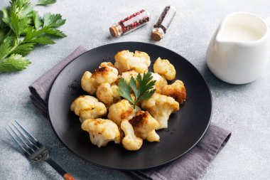 Kızarmış karnabahar çiçekleri siyah bir tabakta hamurda. Gri beton arkaplan Boşluğu kopyala.