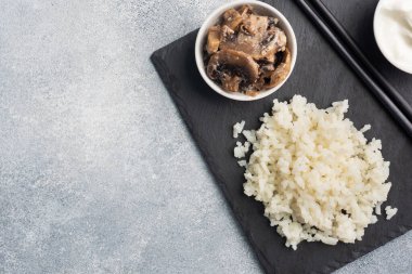 Siyah bir büfede çubuklarla kaynamış beyaz pirinç ve ekşi krema. Gri beton arkaplan Boşluğu kopyala.