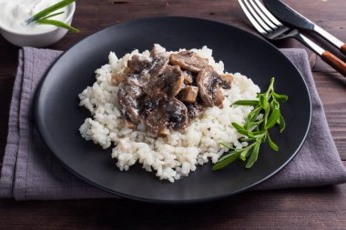 Siyah tabakta mantarlı risotto. Kaynamış beyaz pirinç ve krema soslu şampiyonlar. Koyu tahta arkaplan.