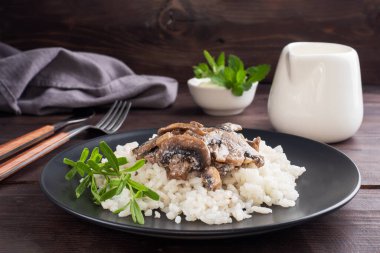 Siyah tabakta mantarlı risotto. Kaynamış beyaz pirinç ve krema soslu şampiyonlar. Koyu ahşap arka plan. Boşluğu kopyala