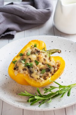 Pirinç mantarlı tatlı biber ve otlu peynir. Doldurulmuş sarı biberli fırında yarımlar. Beyaz tahta arkaplan.