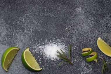 Taze limon dilimleri, tuz ve biberiye koyu beton arka plan. Uzayı kopyala Tekila kokteyli yapmak için gerekli malzemeler.