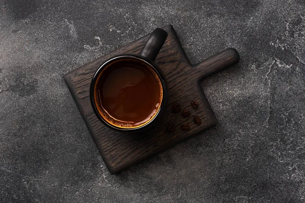 Caffè nero in una tazza e chicchi di caffè su uno sfondo scuro. Vista dall'alto Copia spazio. — Foto Stock