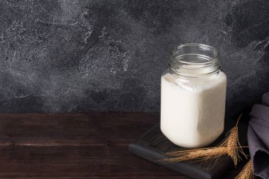 Koyu arkaplanda süt bulunan cam kavanoz. Boşluğu kopyala.