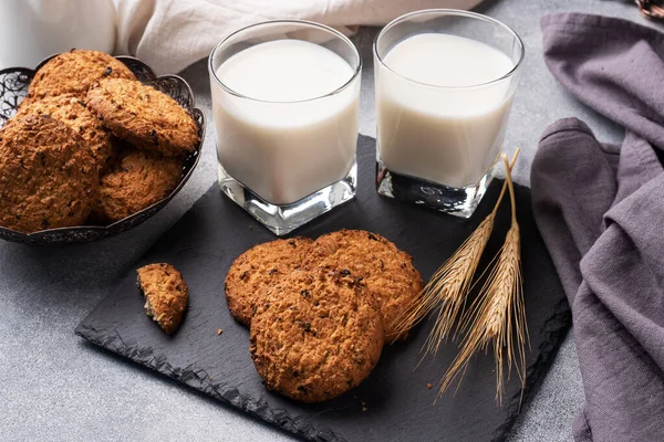 Домашнее печенье из овса и стакан молока на сером бетонном столе. — стоковое фото