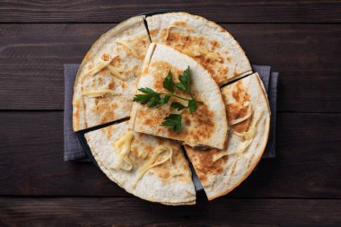 Peynirli ve mantarlı Quesadilla parçaları maydanoz yapraklı bir tabakta. Ahşap arkaplan kopyalama alanı.