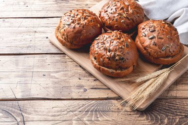 Tahta zemin üzerinde tahıl ve tohum olan ekmek ürünleri. Sağlıklı çörekler, karbonhidratlı hamur işleri. Boşluğu kopyala