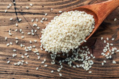 Tahta kaşıkta doğal susam tohumları. Tahta masa. Boşluğu kopyala.