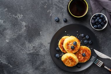 Yabanmersinli süzme peynirli börek. Peynirli peynirli kekler, koyu beton arka planda krepler. Boşluğu kopyala.