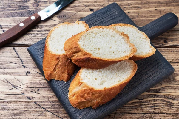 Frisches Weißbrot-Baguette auf einem Holzschneidebrett geschnitten. — Stockfoto