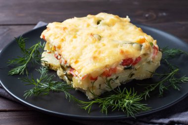 Peynirli patates ve sebzeli güveç. Koyu ahşap arka plan. Kapat..