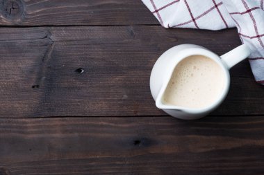 Beyaz seramik süt sürahisi ve taze süt. Koyu ahşap kırsal masa. Boşluğu kopyala.