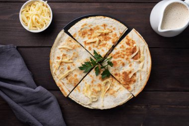 Peynirli ve mantarlı Quesadilla parçaları maydanoz yapraklı bir tabakta. Ahşap arkaplan kopyalama alanı