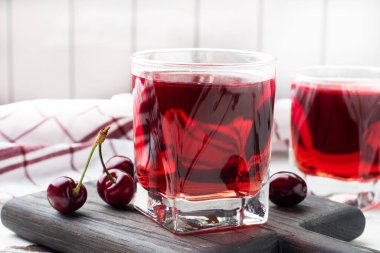 Bardakta kiraz suyu ve taze kiraz meyvesi. Beyaz arka plan. Boşluğu kopyala.