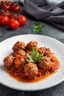 Tabakta domates sosuyla pişirilmiş köfte köftesi. Koyu beton arkaplan.