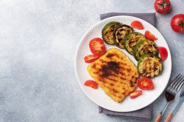 Izgarada kızarmış tavuk ve kabak şnitzel. Tabakta taze domates. Lezzetli bir öğle yemeği hazırlayın..