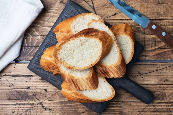 Fresco pane bianco baguette taglio uccisioni su un tagliere di legno. — Foto Stock