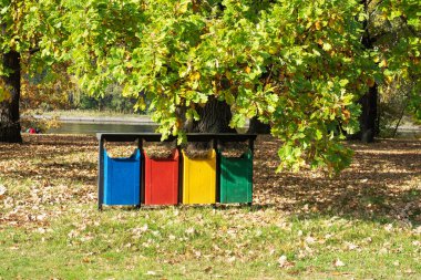 Parktaki eski renkli geri dönüşüm kutuları. Ayrı çöp koleksiyonu için vazolar.