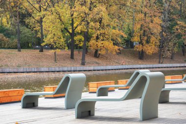 Sonbahar parkında dinlenmek için banklar ve güneş yatakları..