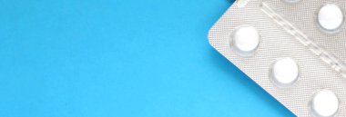 Mavi arka planda, yumuşak odaklı beyaz tabletler. Metin için boşluk.