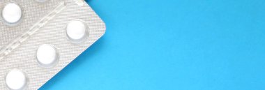 Mavi arka planda, yumuşak odaklı beyaz tabletler. Metin için boşluk.