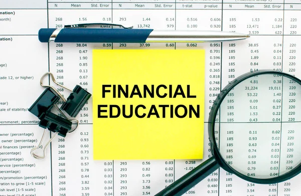 Text Financial Education on financial tables with pen, puper clips and magnifying glass. Business and financial conzept