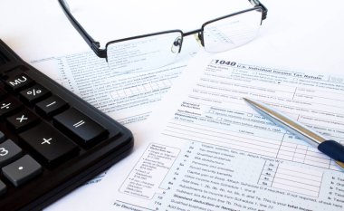 Amerikan vergi formu 1040 gümüş kalem, gözlük ve hesap makinesiyle