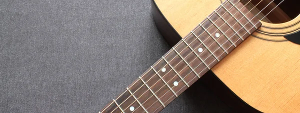 Gri ahşap arka planda mavi bir akustik gitarın parçası.