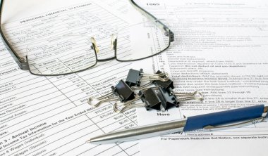 Siyah ofis klipleri ve gözlüklerle finans masalarında mavi metal bir kalem duruyor. İş ve finansal konsept.