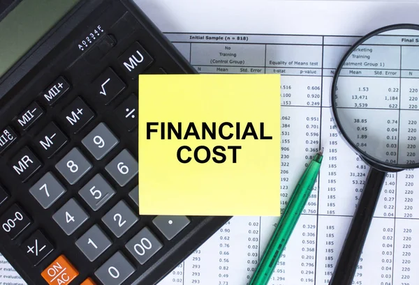 Naklejka Tekstem Koszt Finansowy Leżący Kalkulatorze Szkło Powiększające Zielonym Długopisem — Zdjęcie stockowe