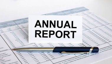 Finansal tablonun üzerinde mavi metal kalem olan beyaz kart hakkında yıllık metin raporu. İş ve mali konsept