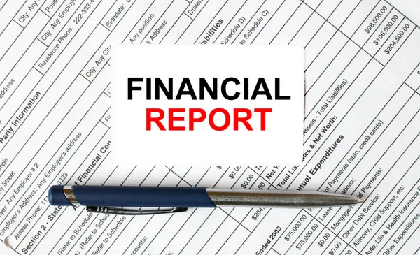 Text Financial Report written on a business card lying on financial tables with a blue metal pen. Business and financial concept