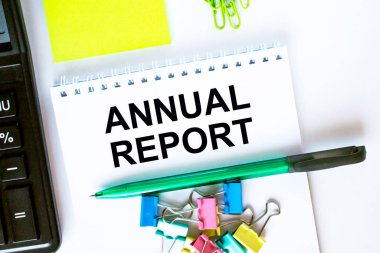 Yıllık raporlu bir not. Hesap makinesi, yeşil kalem etiketleri ve kırtasiye klipsleri. İş ve mali konsept