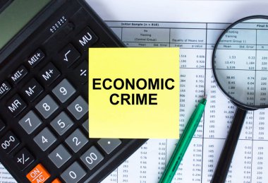 Hesap makinesinde yazılı Ekonomik Suçlar etiketi var. Finansal belgelerde yeşil kalemli büyüteç. İş ve mali konsept