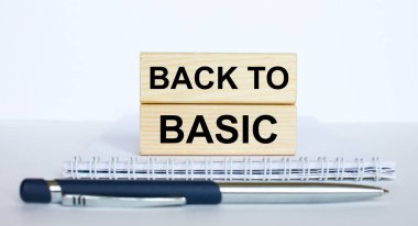 Metin Backto Basic, metal mavi bir kalemle bir not defterinin üzerinde duran jenga ahşap bir çubuğun üzerinde. İş konsepti fotoğrafı