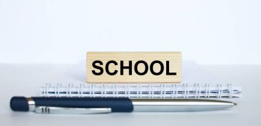 Metal mavi kalemle bir not defterinin üzerinde duran jenga ağacının üzerindeki okul kelimesi. İş konsepti fotoğrafı