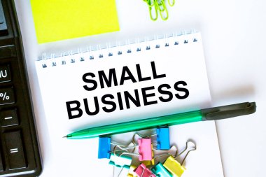 Küçük İşletme ile ilgili bir not. Hesap makinesi, yeşil kalem etiketleri ve kırtasiye klipsleri. İş ve mali konsept