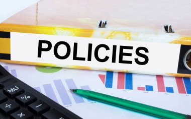 Finansal diyagramlarda yeşil kalem ve hesap makinesiyle yer alan klasördeki metin politikaları. İş ve mali konsept
