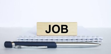 Metal mavi kalemle bir not defterinin üzerinde duran Jenga odununun üzerindeki Job kelimesi. İş konsepti fotoğrafı