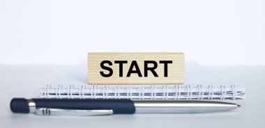 Metal mavi kalemle bir not defterinin üzerinde duran jenga ağacından bir çubuk üzerinde başla. İş konsepti fotoğrafı