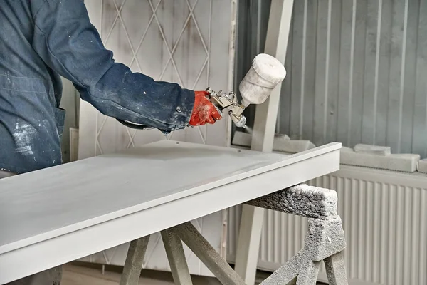 Painting cabinets with spray gun. Painting chamber, spray gun. Wooden furniture manufacturing process