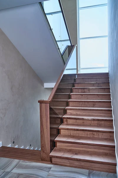 Part of wooden steps with glass railings. Walnut staircase