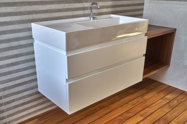 Wall mounted bathroom vanity in luxury bathroom with teak floor. Stylish interior of modern bathroom. Details furniture