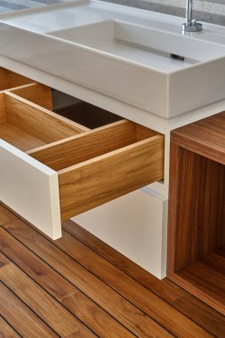 Wall mounted bathroom vanity in luxury bathroom with teak floor. Stylish interior of modern bathroom. Details furniture